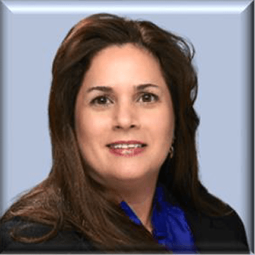 Professional headshot of a woman with long brown hair, smiling against a light blue background. Relevant for a business or organizational profile.